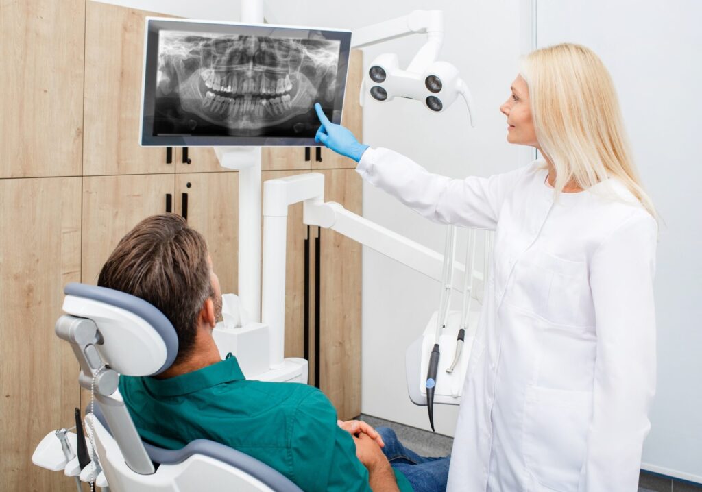 Beautiful woman dentist consulting a man patient, patient has a wisdom tooth ache. Treatment or