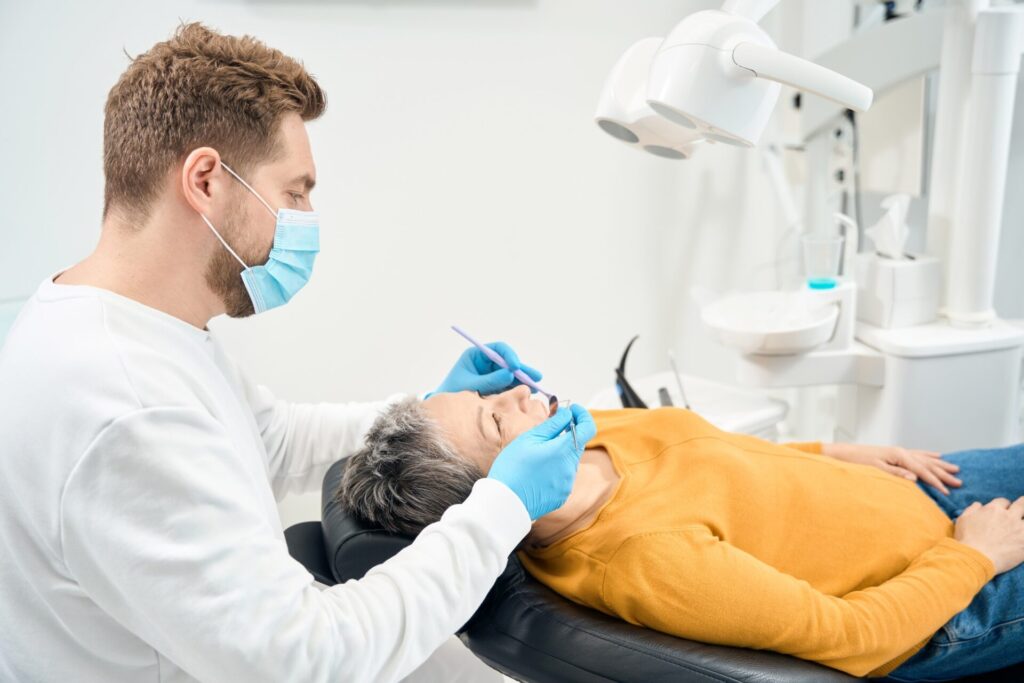Dental therapist keeping out routine check-up of teeth and gums